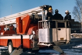 Mölndals brandstation i Trädgården, Mölndal, på 1980-talet. Tre brandmän står i brandbilens lift.