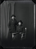 Två kvinnor i hattar och kappor