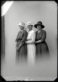 Tre unga kvinnor i tjusiga hattar