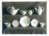 Teservis från Bo Fajans, tidigt 1900-tal. Tekannor, skålar, koppar och fat. På bilden har dekoren ritats i med en grön penna.