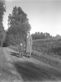 Mormor med barnbarn på en grusväg.