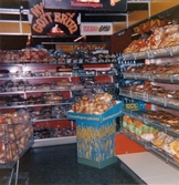 Brödavdelningens vägghyllor är fyllda av olika slags bröd, Domus Mölndal C efter 1976. Ovanför en hylla hänger en skylt med 