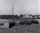 Ett lass med tunnor vid en brygga, troligen vid oskarshamnskusten.