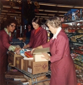 Tre expediter klädda i röda rockar (Berit Thörnqvist längst till höger), packar upp kaffebröd i brödavdelningen, Domus Mölndal C efter 1976.