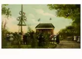 Midsommarfirande på Gamla Påskberget med flera kransar på midsommarstången. Serveringspaviljongen på bilden användes under Lantbruks- och Industriutställningen 1904 i Varberg på Gamlebygärdet och placerades efteråt på Påskberget.