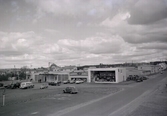 Varberg, Kv Björnen, Getakärrsplatsen. I förgrunden Modins bilförsäljning- verkstad. (Ärlebo Bil AB, 1999). I bakgrunden kv Älgen med transformatorhuset. 1950-tal.