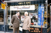 Storgatan, Växjö. Nils Hyltén-Cavallius pratar med en herre på trottoaren. I bakgrunden syns en av de nya affärerna i kv. Unaman.
Färgfoto ca 1970.