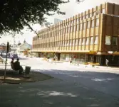 Storgatan, Växjö, i korsningen mot Västra Esplanaden. Till höger syns det nya Valandhuset i kvarteret Tegnér. Man håller på att reparera stensättningen i gatan.