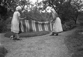 Under vårstädningen skakas matta i Karlstorp, 1940-tal