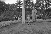 Elna Blomé med flicka i trädgården i Lysinge, 1940-tal