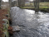 Vy söderut på Mölndalsfallen och dess stensättning, Mölndal år 2011. En något upphöjd sten ligger i forsen. Till vänster ses träd utmed parkeringen på Pixbovägen 7. Dokumentation inför ombyggnation.
Relaterade motiv: 2024_1365 - 1412.