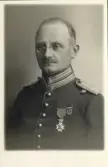 En man med pincené, klädd i full uniform.
Ateljéfoto.
Musikdirektör Oskar Georg Alm.
Född 1877. Kom i tjänst som musiksergeant 1902.
Senare musiksergeant - fanjunkare - musikdirektör vid I 7 (Karlskrona grenadjärregemente).
Avsked med pension 1927.