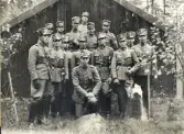 En grupp militärer (officerare?) har samlats för ett gruppfoto, i samband med någon form av kurs/skola?. 
6 oktober 1936. 
(Enligt lista på baksidan:) Fr.v. (1935-37:) 1. Vingren, 2. Lindquist, 3. Hofvendahl, 4. Olson, 5. Hammarberg, 6. Kjellberg, 7. Linell, 8. Nilsson, (1936-38:) 9. Palmqvist, 10. Nilsson, 11. Aaby-Ericsson, 12. Gyllensvärd, 13. Eidelin, 14. Löwenadler. (1937-1939:) 15. Fornander.