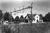 Åsa järnvägsstation omgiven av träd med spåren i förgrunden. Åsa ligger utmed Göteborg-Hallands järnväg som stod klar 1888, sista pusselbiten i det som senare skulle komma att kallas Västkustbanan och som förstatligades 1896.