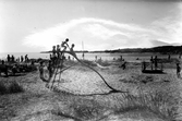 Åsa havsbad. Strandvy med sandstrand och badande. Rutschkana i sanden.