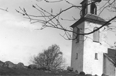 Kyrktornet på Gällinge kyrka med en flock fåglar i skyn.