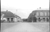 Torggatan sedd från torget och med kv Apotekaren till vänster och kv Rådhuset till höger. Fasaderna i bild ligger utmed Drottninggatan.