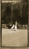 Lizzie spelar tennis framför åskådare, 1918