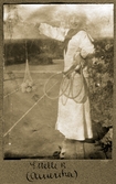 Estelle med tennisracket och bollar i nät på tennisbanan, 1918