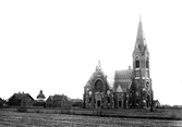 Falkenbergs kyrka som tämligen ny. Den invigdes 14 oktober 1892 och ritades i nygotisk stil av arkitekt Adrian C Peterson. I bakgrunden syns prästgården, stinsbostaden och tornet på stadens medeltida kyrka, S:t Laurentii.