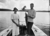 Kvinna och man på båt med en nyfångad fisk, Uppsala