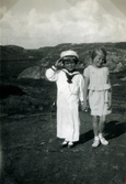 Två små barn står på en bergsknalle, okänd plats 1939 - 1941. Pojken som är klädd i sjömanskläder gör honnör. Flickan bär klänning. Troligtvis barn till Aina Englund (1914 - 2012), vårdbiträde/undersköterska på Mölndals lasarett 1939 - 1941. 
Relaterade motiv: 2024_1542 - 1617.