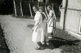 Tre kvinnliga sjukvårdsbiträden går på en grusgång utanför Mölndals sjukhus 1939 - 1941. Till vänster ses Ester Johansson (1914 - 2008, gift Faldahl). Bilder från fotoalbum, tagna från södra sidan av Länsmansgatan vid Mölndals lasarett/sjukhus 1939 - 1941 på bland annat givarens mor Ester (född Johansson) tillsammans med kollegan/väninnan Aina Englund. De arbetade på den manliga kirurgavdelningen som vårdbiträden/undersköterskor.
Relaterade motiv: 2024_1542 - 1617.