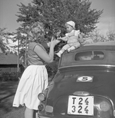 Kvinna med barn vid bilen i Karlstorp, 1950-tal