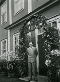 Johan Gripenstedt står i blomsterportal på Bystad efter att ha tagit examen, 1940