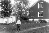 Pojke med cykelhjul vid biodlingen hos Charles Andersson, 1929