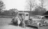 Familjefoto vid bilar i Norrbyås, 1950-tal