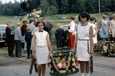 Krans, tupp och flöjel bakom flickor med krans till midsommarstång, ca 1967