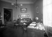 Interiör från Araby herrgård. Arbetsrum/herrum med skrivbord, soffmöblemang m.m. 
Man ser ut i hallen. Ca. 1910.