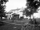 Några personer framför bostadshus på okänd plats i Kronobergs län, ca 1905.