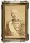 Ett inramat foto (med autograf) av kung Oscar II (1829-1907), reg. 1872-1907.
Bröstbild, ateljéfoto.
På baksidan ett inramat brev med kungens namnchiffer överst: 