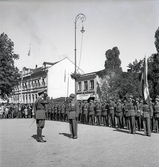 Mottagande av kronprins Gustaf Adolf med gemål Louise
på stationen i Växjö, i samband med jubileumsutställning m.m.
Kronprinsen möter hederskompaniet på järnvägsplanen. 

Gustaf VI Adolf (1882-1973), reg. 1950-1973.
G.m. 2:o Louise, f. Mountbatten (1889-1965).