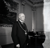 En äldre man har ställt sig upp för att fotograferas.
Han har mörk kostym med stärkkrage och på bröstet
en ordenskedja (?) med medalj. 
Borgmästare Theodor Sundberg (1875-1948) (?).