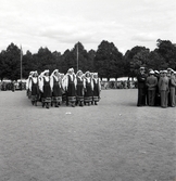 Jubileumsutställningen. Invigningen. 
Ett antal kvinnor i Värendsdräkt tågar in på planen framför
hedersläktaren.