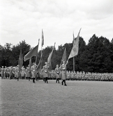 Jubileumsutställningen. Invigningen. 
Ett antal kvinnor i lottauniform tågar in på planen framför hedersläktaren.