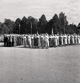 Jubileumsutställningen. Invigningen. 
Vy över skolgården till Växjö Högre Allmänna Läroverk. 
Man ser en mängd kvinnor i husmorsdräkt och bakom dem en manskör.