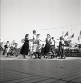 Jubileumsutställning. 
Folkdansuppvisning. Ett folkdanslag i Värendsdräkt m.m. visar upp
sig på en dansbana.