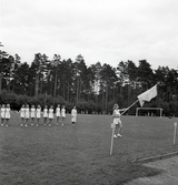 Parad med fana framför en kvinnlig gymnastiktrupp under Gymnastikens dag.