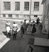 Några kvinnor i s.k. husmorsdräkter har samlats utanför
dåv. Flickskolan (Graffmanska skolan) i Växjö.