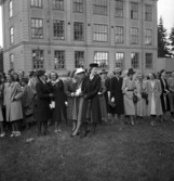 Ett antal uppklädda damer har samlats för skolträff, på skolgården utanför
Flickskolan (Graffmanska skolan) i Växjö.