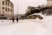 Ett par promenerar nerför Kråkan i Mölndals Kvarnby efter snöstormen den 17 november 1995. Till vänster byggnaden 