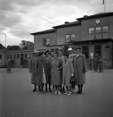 Ett antal uppklädda damer har samlats vid järnvägsstationen 
i Växjö, i samband med skolträff.