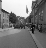 Hantverkets dag. En musikkår m.m. är på väg längs Norrgatan västerut. En polis går längs trottoaren.