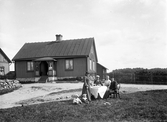 Elias Fredrik Gustafsson med familj framför sitt bostadshus i Älmhult, ca 1910.