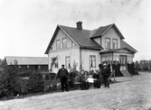 Familj framför okänt bostadshus, tidigt 1900-tal.