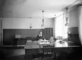 Kvinna sitter vid skrivbord, okänt kontor i Växjö. Ca. 1920.